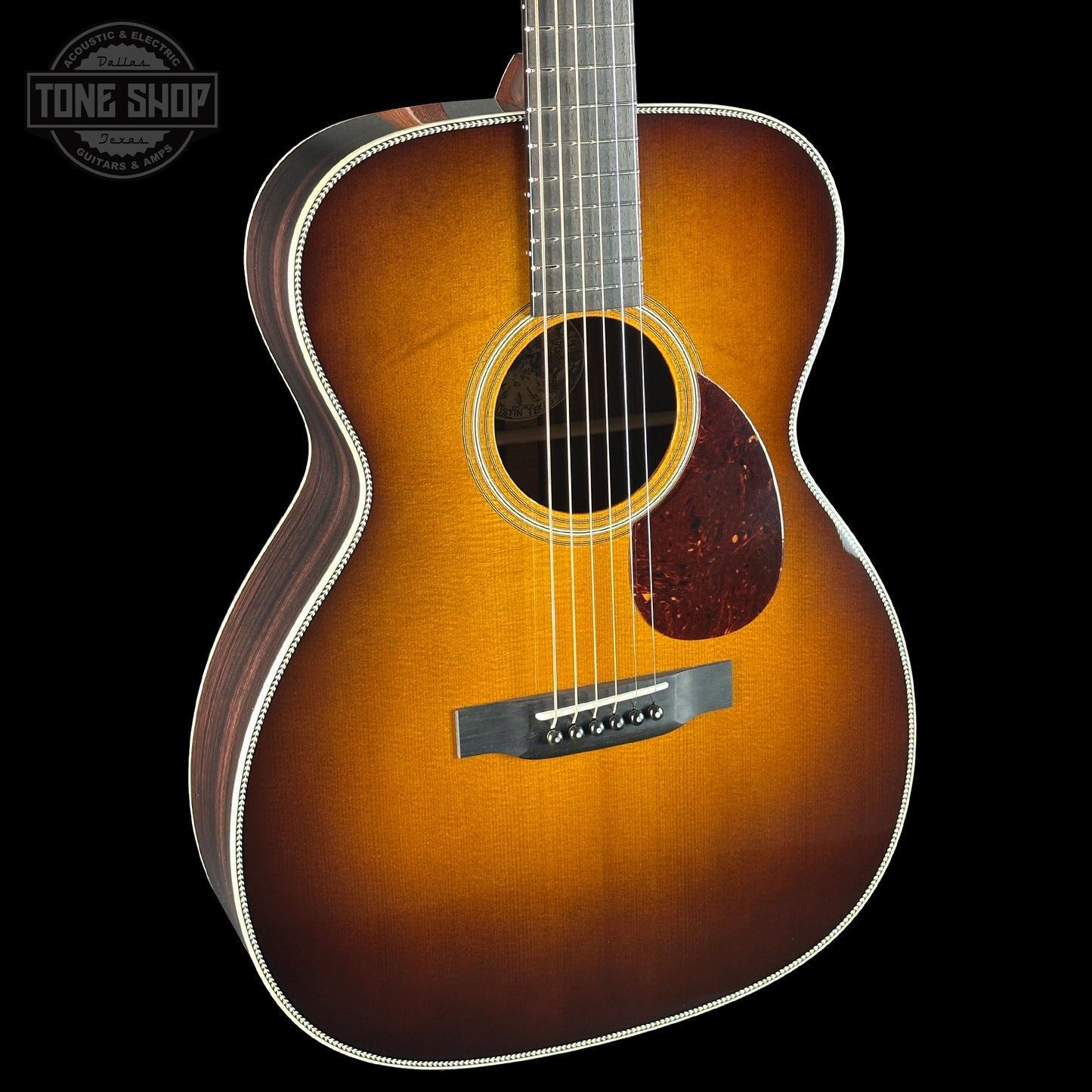 Acoustic guitar with a sunburst finish on a black background, featuring the Tone Shop logo.