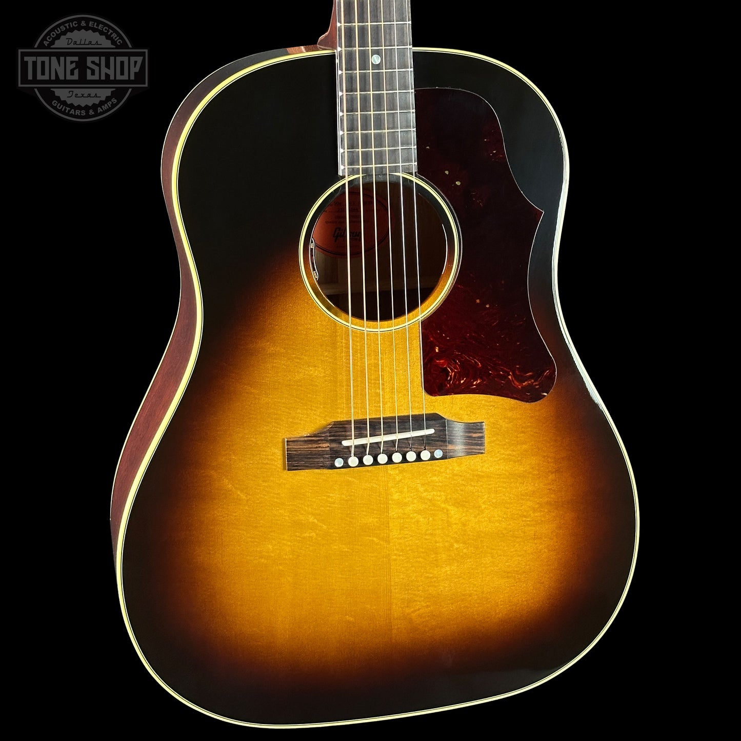 Acoustic guitar with a sunburst finish on a black background, featuring the Tone Shop logo.