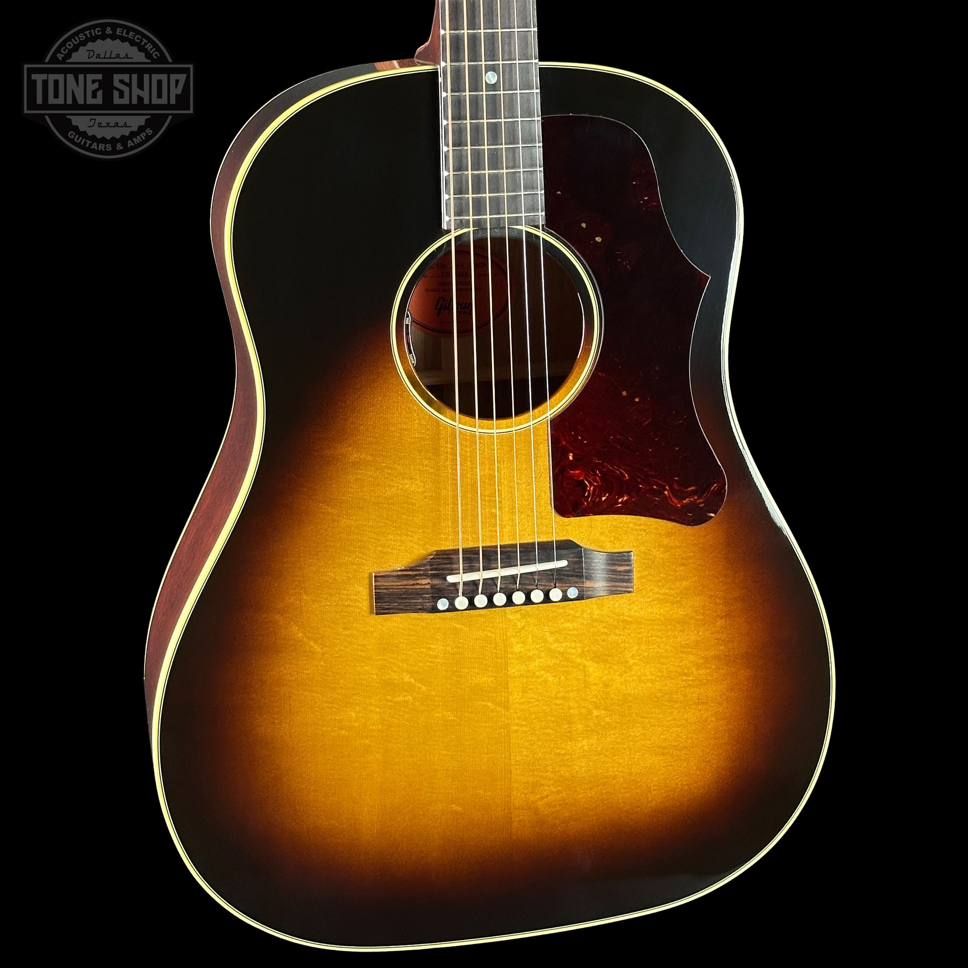 Acoustic guitar with a sunburst finish on a black background, featuring the Tone Shop logo.