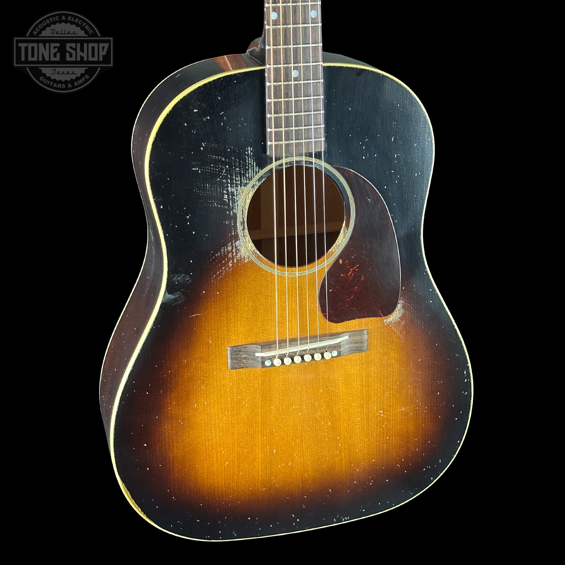 Acoustic guitar with a sunburst finish on a black background, featuring the Tone Shop logo.