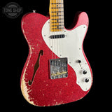 Red glitter electric guitar with a white pickguard on a black background, featuring 'Tone Shop' branding.