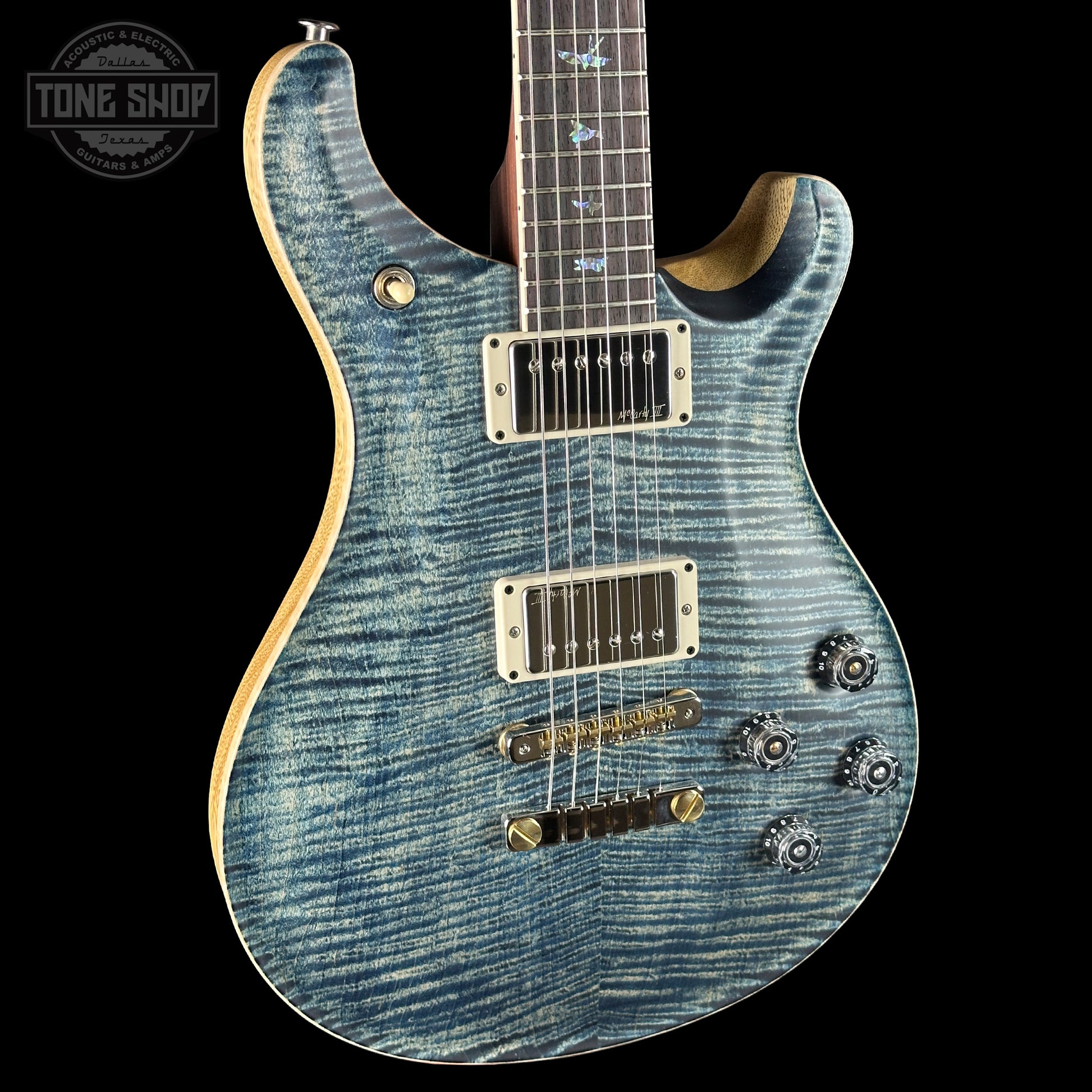 Blue electric guitar with a 'Tone Shop' logo in the corner