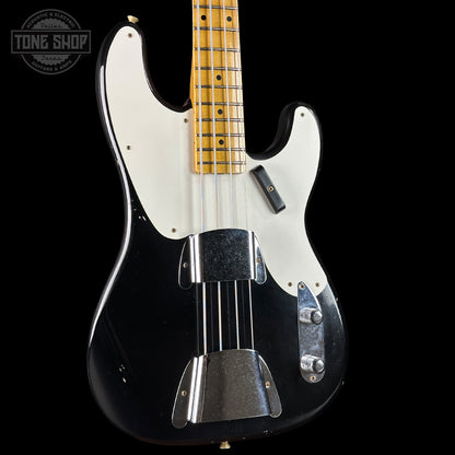 Black electric bass guitar with a white pickguard on a black background, featuring the Tone Shop logo.