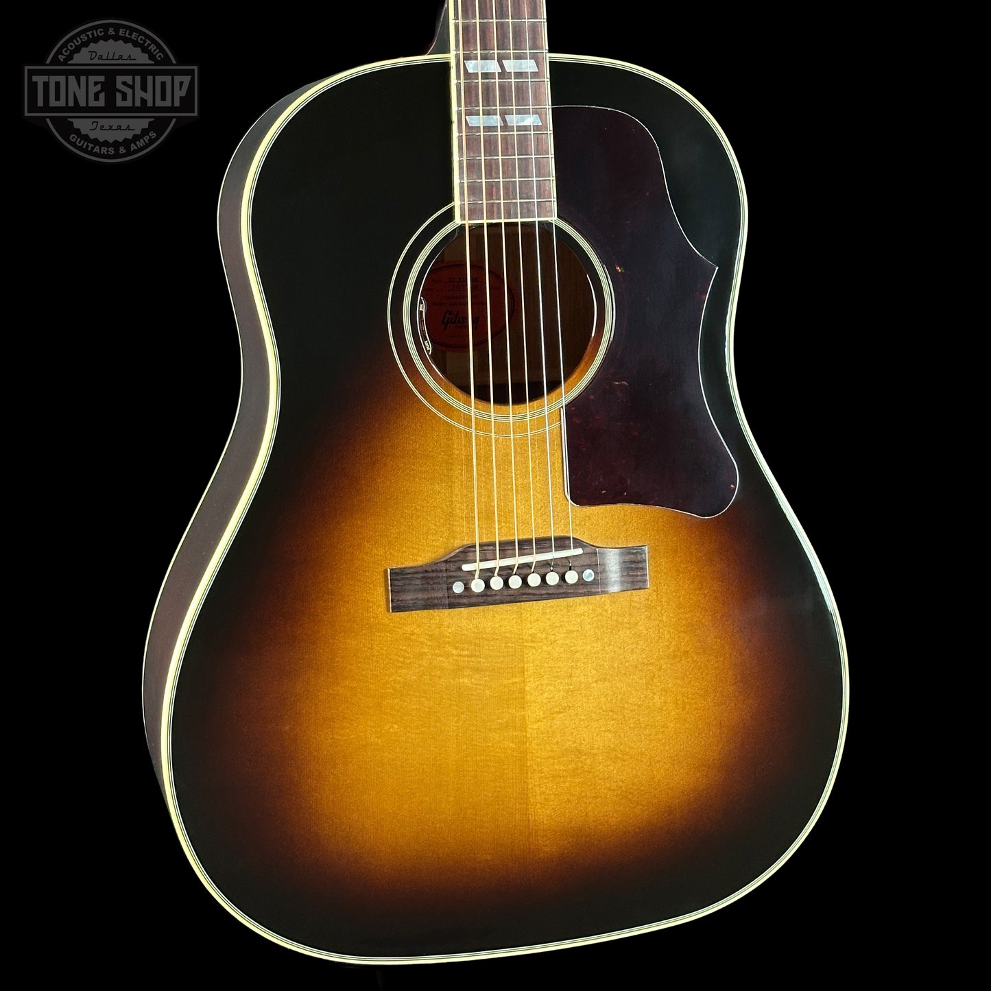 Acoustic guitar with a sunburst finish on a black background, featuring the Tone Shop logo.