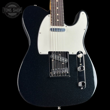 Black electric guitar with a white pickguard on a black background, featuring the Tone Shop logo.
