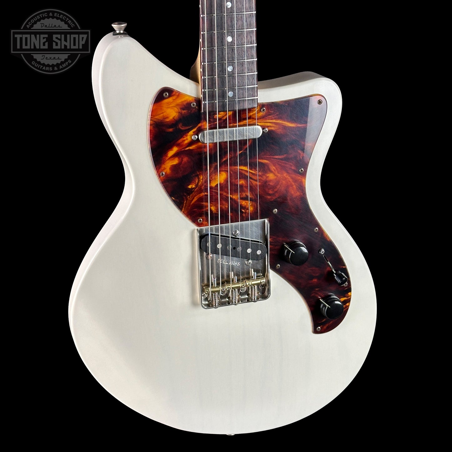 White electric guitar with tortoiseshell pickguard on a black background