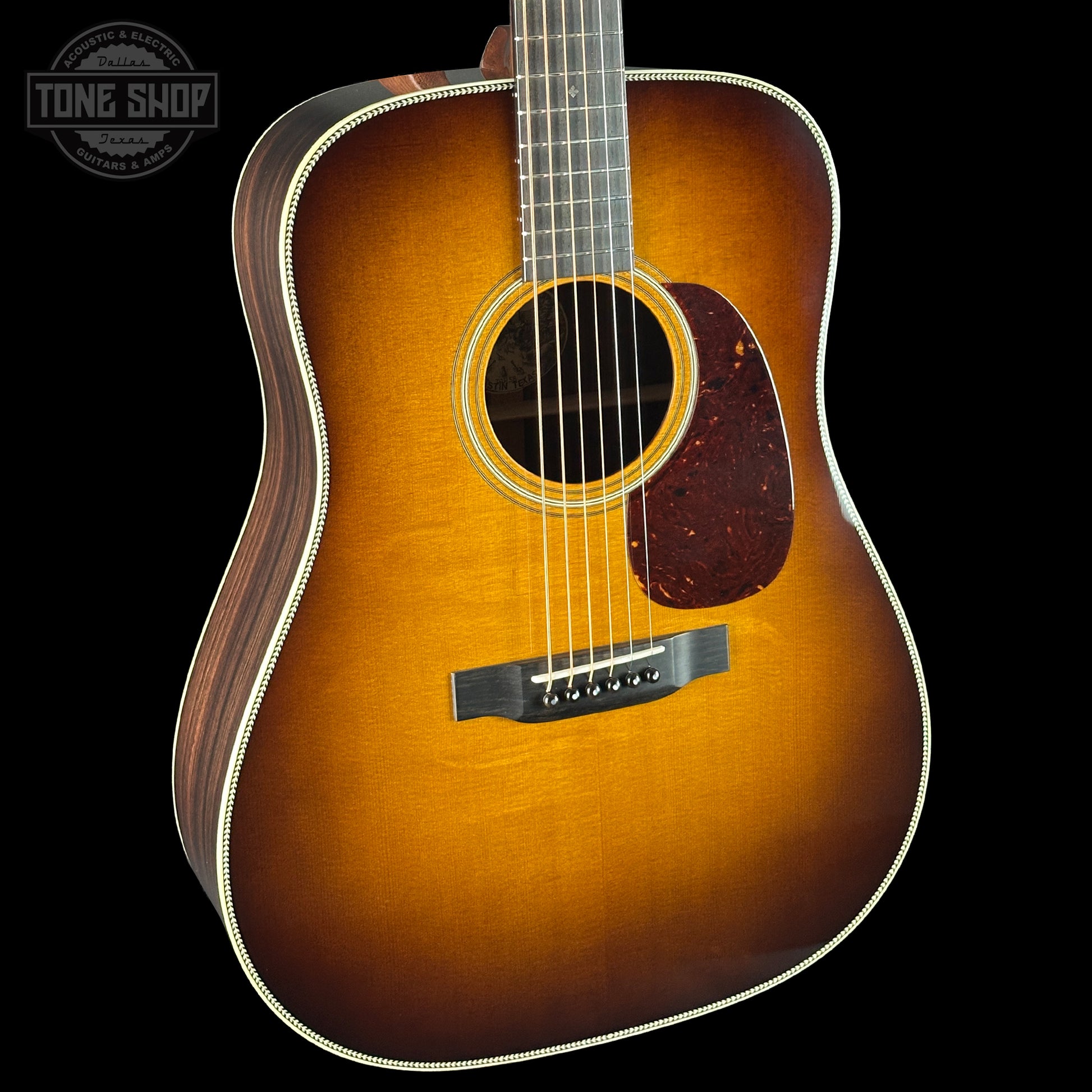Acoustic guitar with a sunburst finish on a black background, featuring the Tone Shop logo.