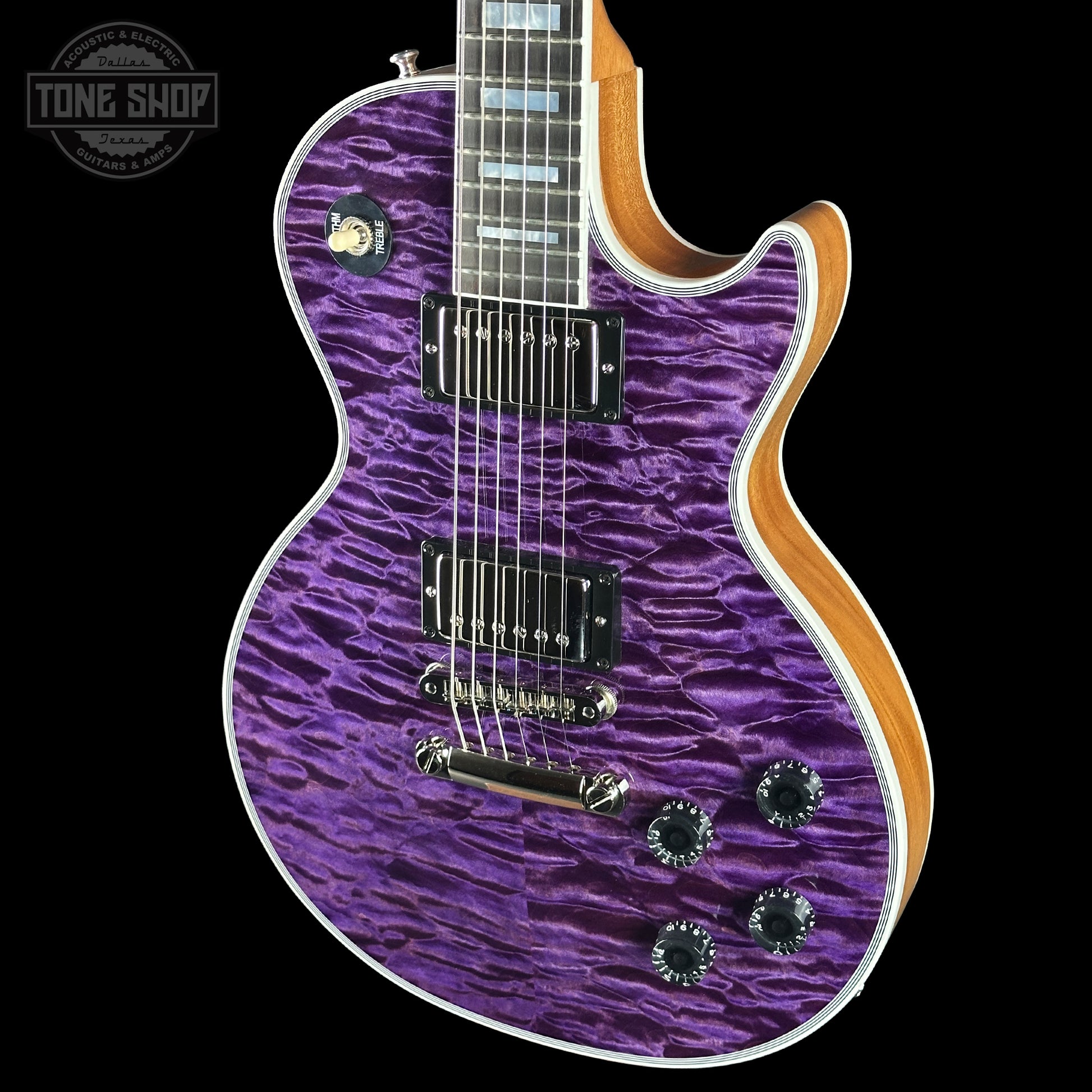 Purple electric guitar with a wavy pattern on a black background, featuring the Tone Shop logo.