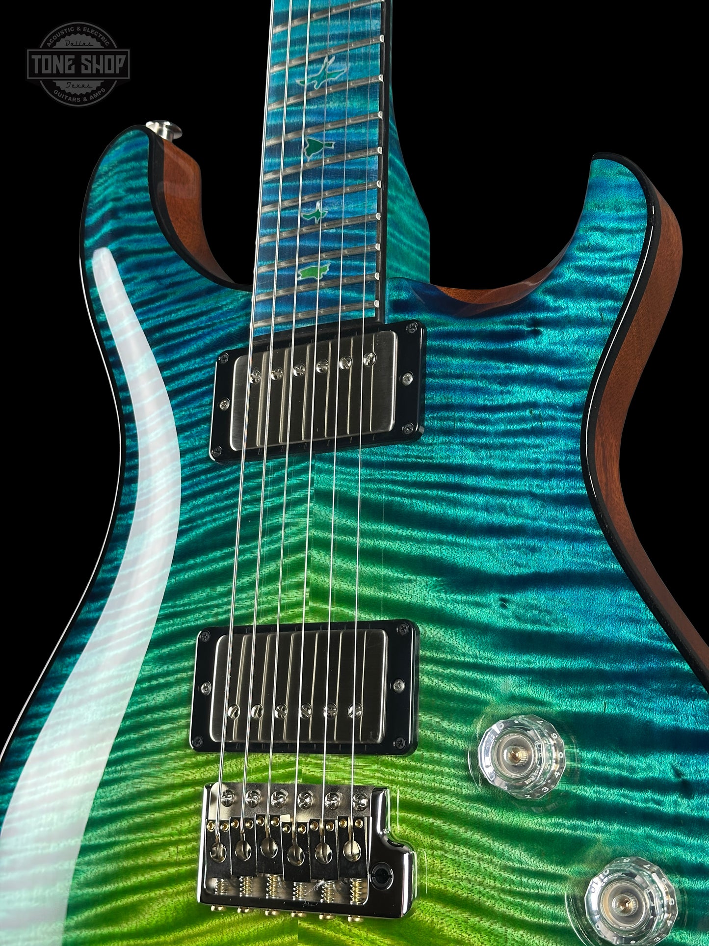 Close-up of a guitar with a wavy green and blue pattern on a black background