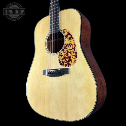 Acoustic guitar with a tortoiseshell pickguard on a black background, featuring the Tone Shop logo.