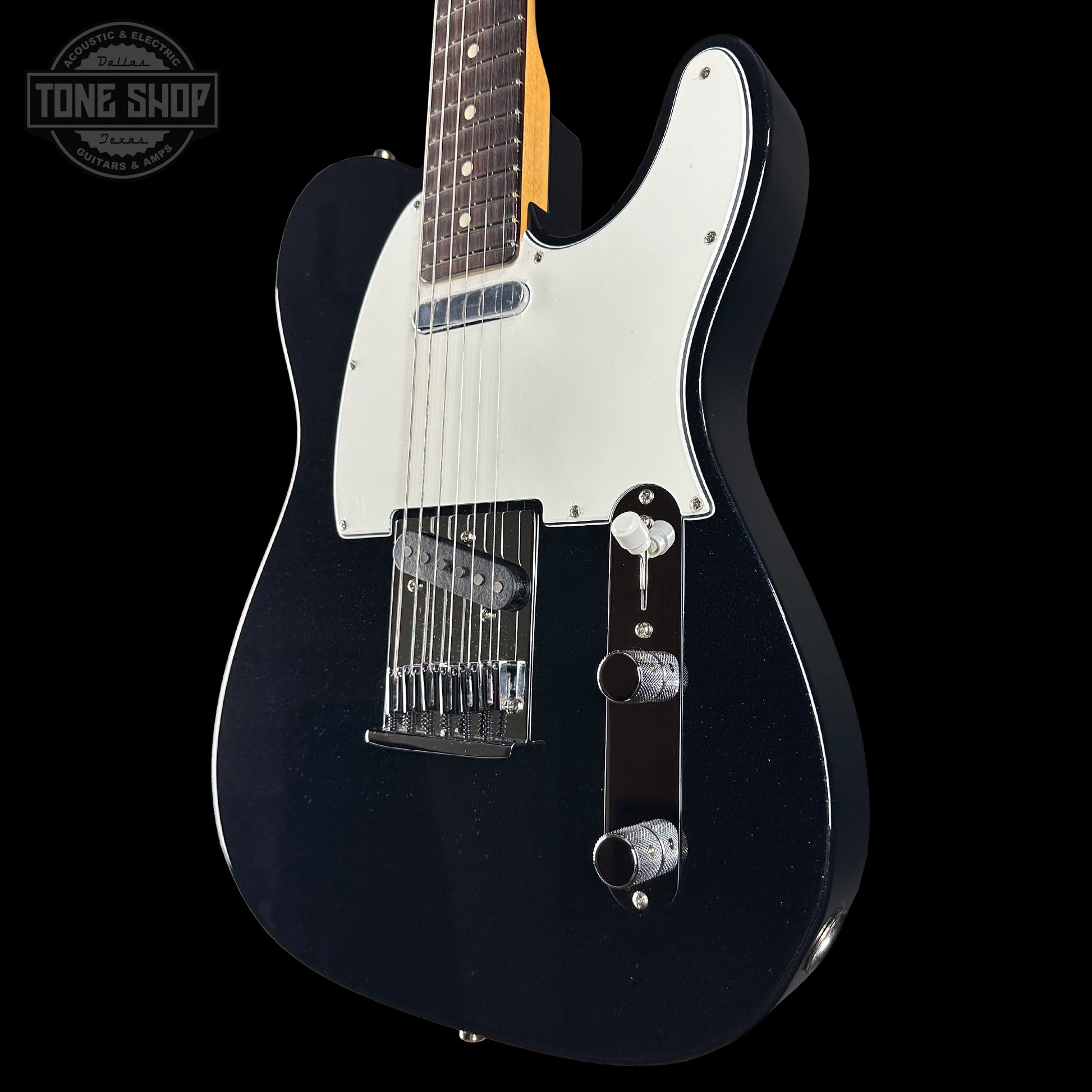 Black electric guitar with a white pickguard on a black background, featuring 'Tone Shop' branding.