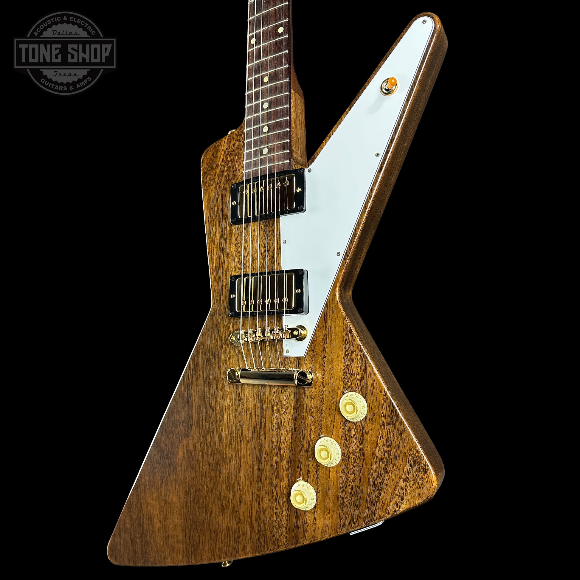 Wooden electric guitar with a white pickguard on a black background, featuring the Tone Shop logo.