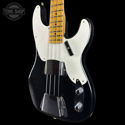Black electric bass guitar with white pickguard on a black background, featuring 'Tone Shop' logo.