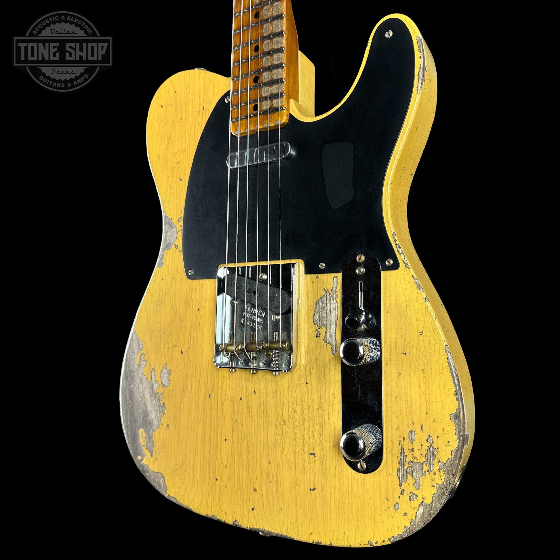 Yellow electric guitar with a worn finish on a black background, featuring 'Tone Shop' logo.
