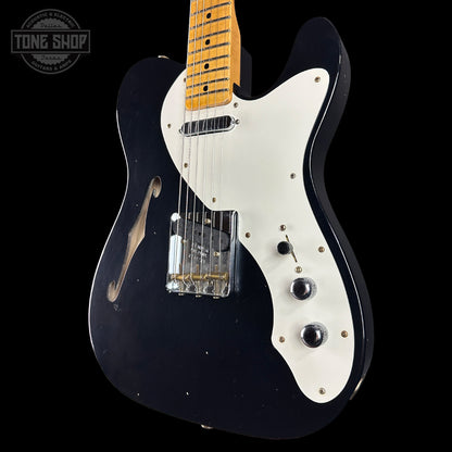 Black electric guitar with white pickguard on a black background, featuring 'Tone Shop' logo.