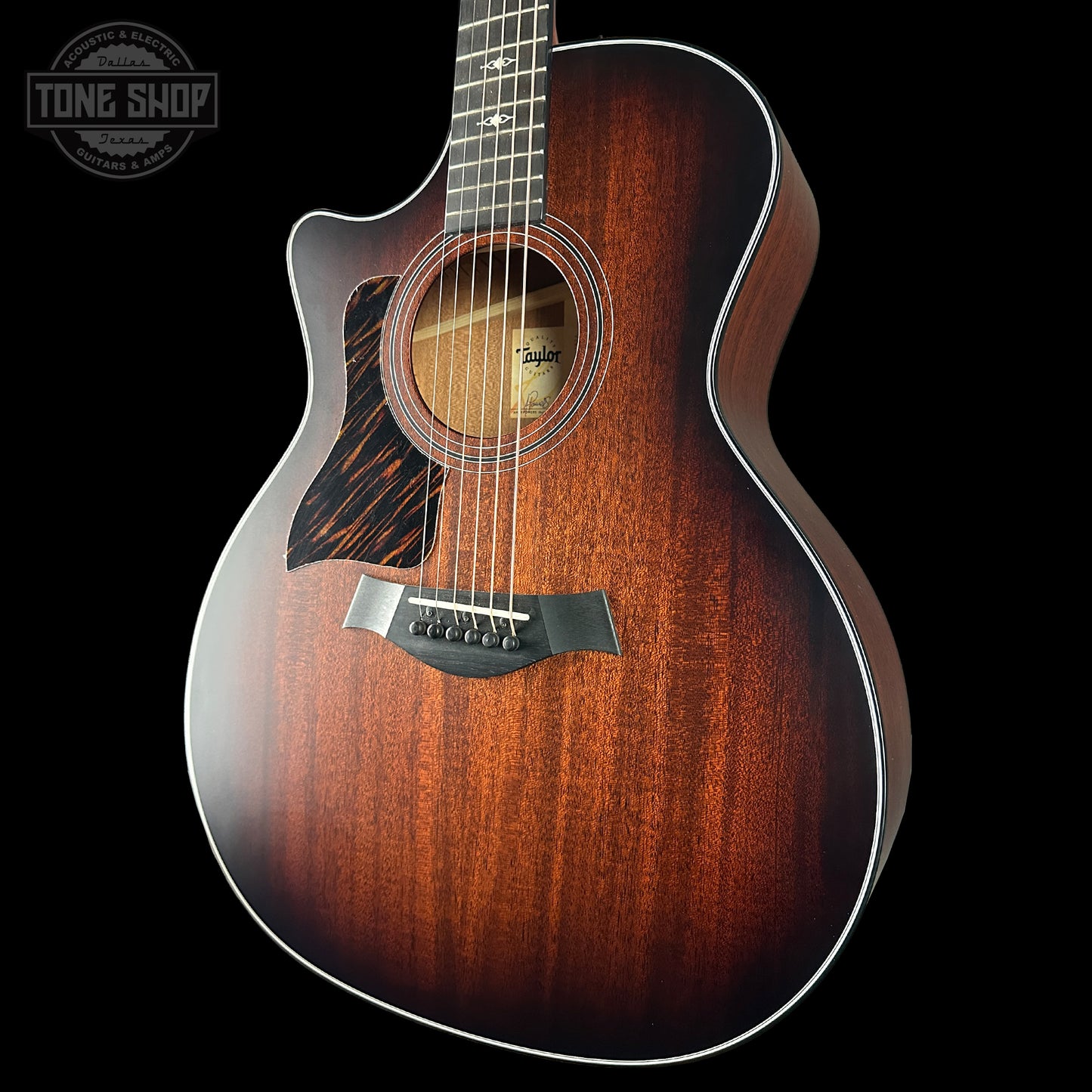 Acoustic guitar with a dark brown finish on a black background, featuring the Taylor brand.