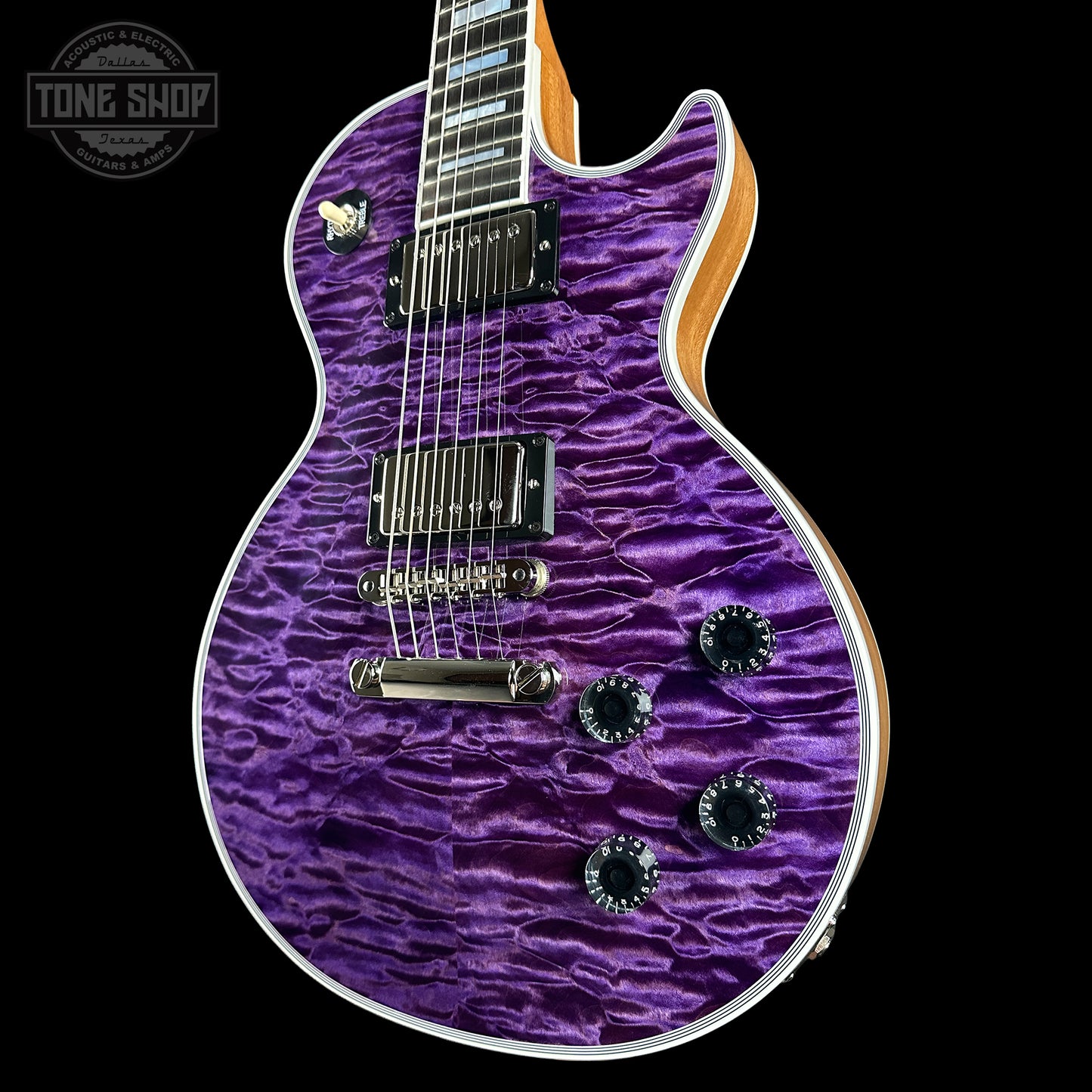 Purple electric guitar with a wavy finish on a black background, featuring 'Tone Shop' branding.