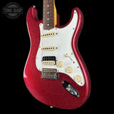 Red electric guitar with a white pickguard on a black background, featuring the Tone Shop logo.
