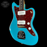 Electric guitar with a turquoise body and brown pickguard on a black background, featuring the Tone Shop logo.