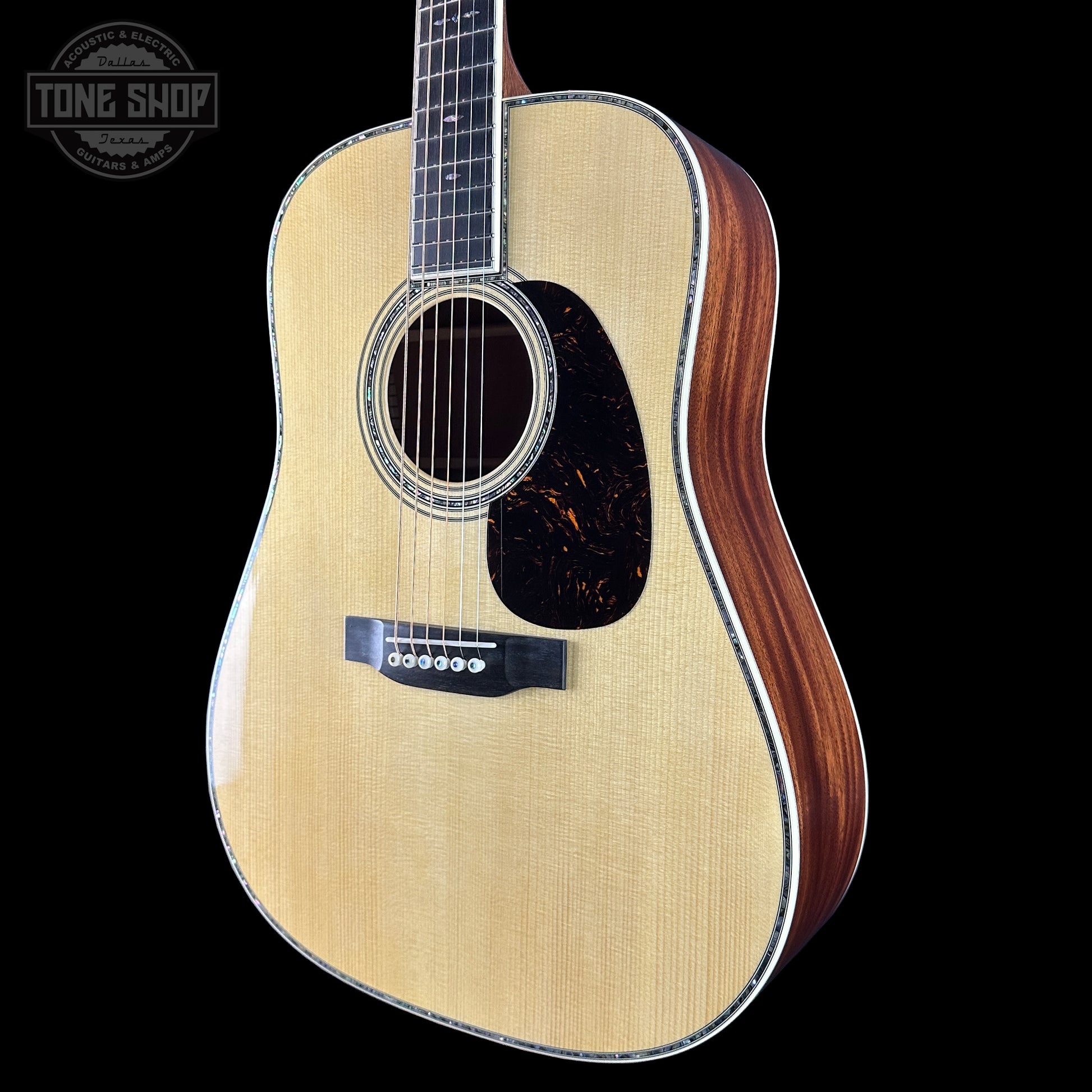 Acoustic guitar with a visible brand logo on a black background