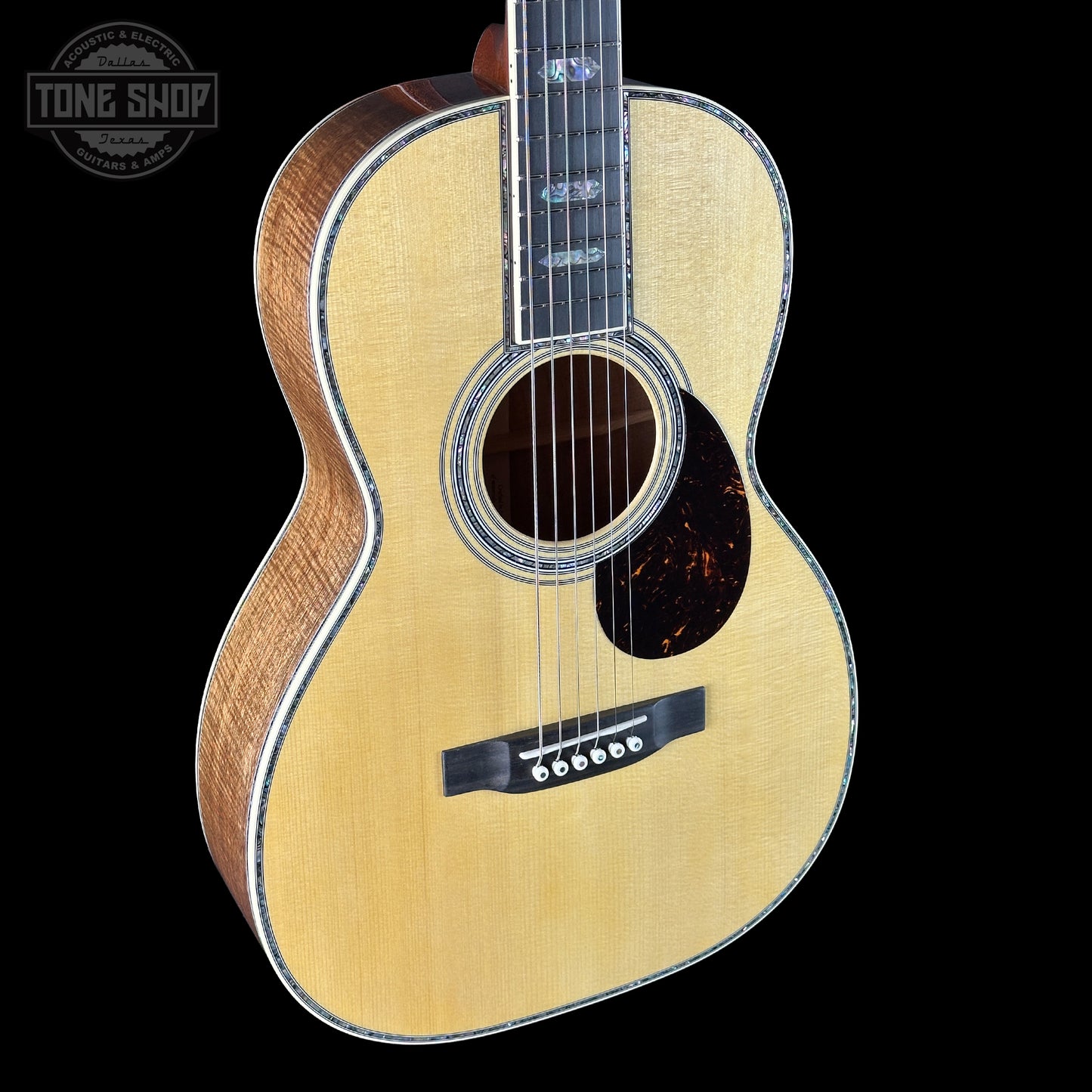 Acoustic guitar with a visible brand logo on a black background