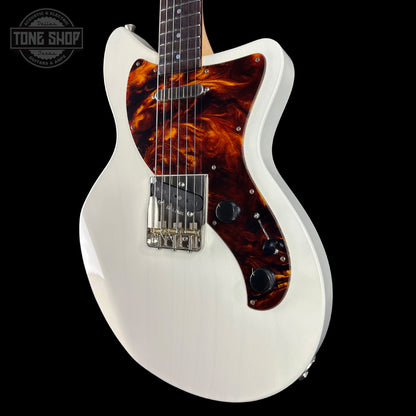 White electric guitar with tortoiseshell pickguard on a black background