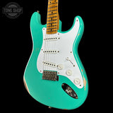 Turquoise electric guitar with a white pickguard on a black background, featuring 'Tone Shop' branding.