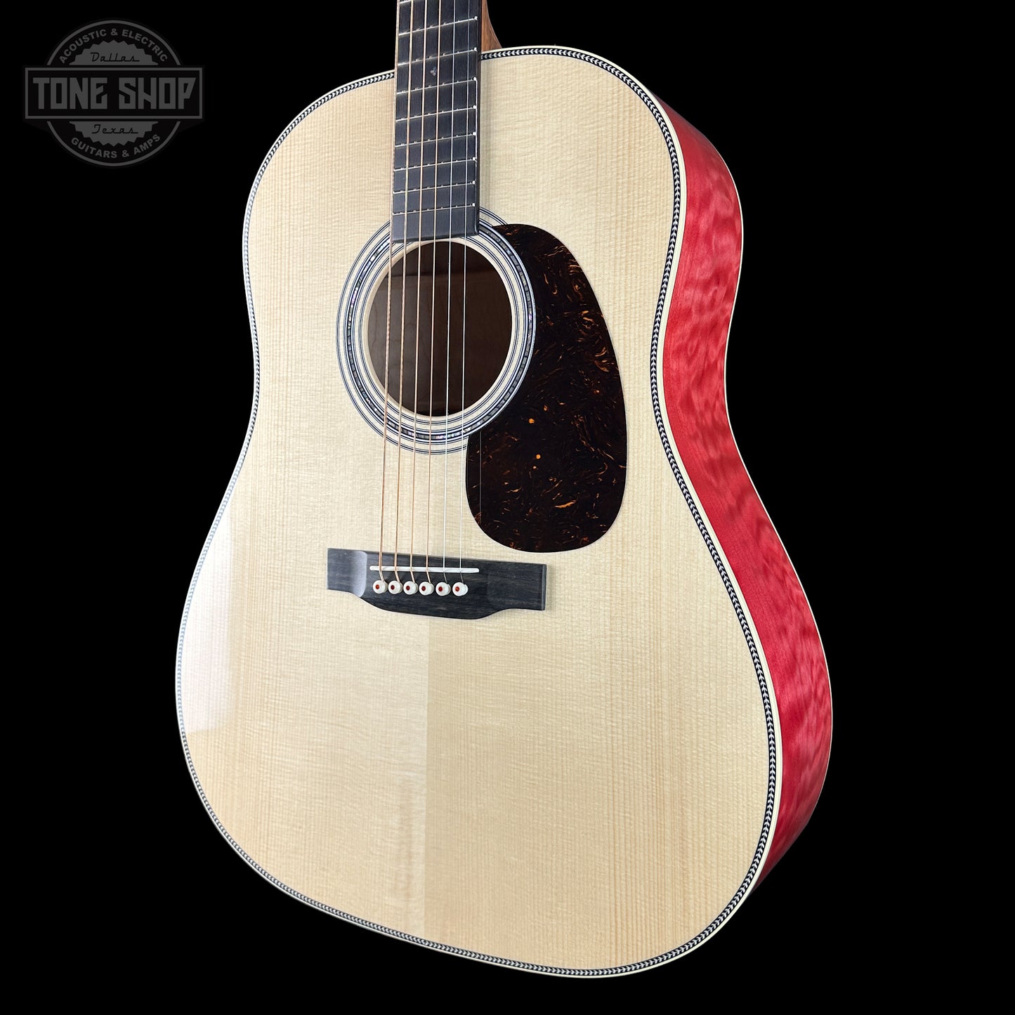 Acoustic guitar with a red binding on a black background, featuring the Tone Shop logo.
