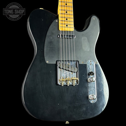 Black electric guitar with a visible brand logo on a black background