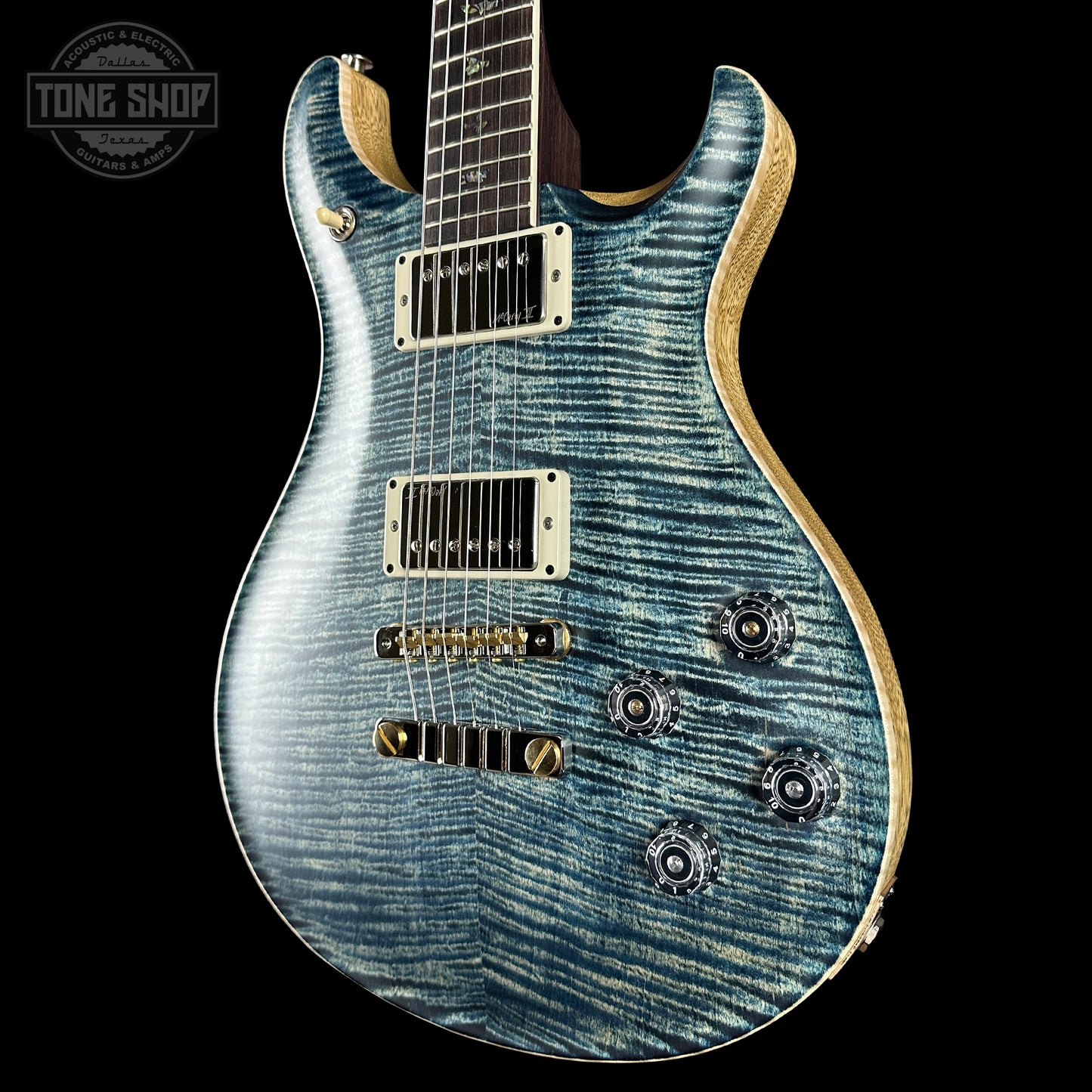 Blue electric guitar with a 'Tone Shop' logo in the corner