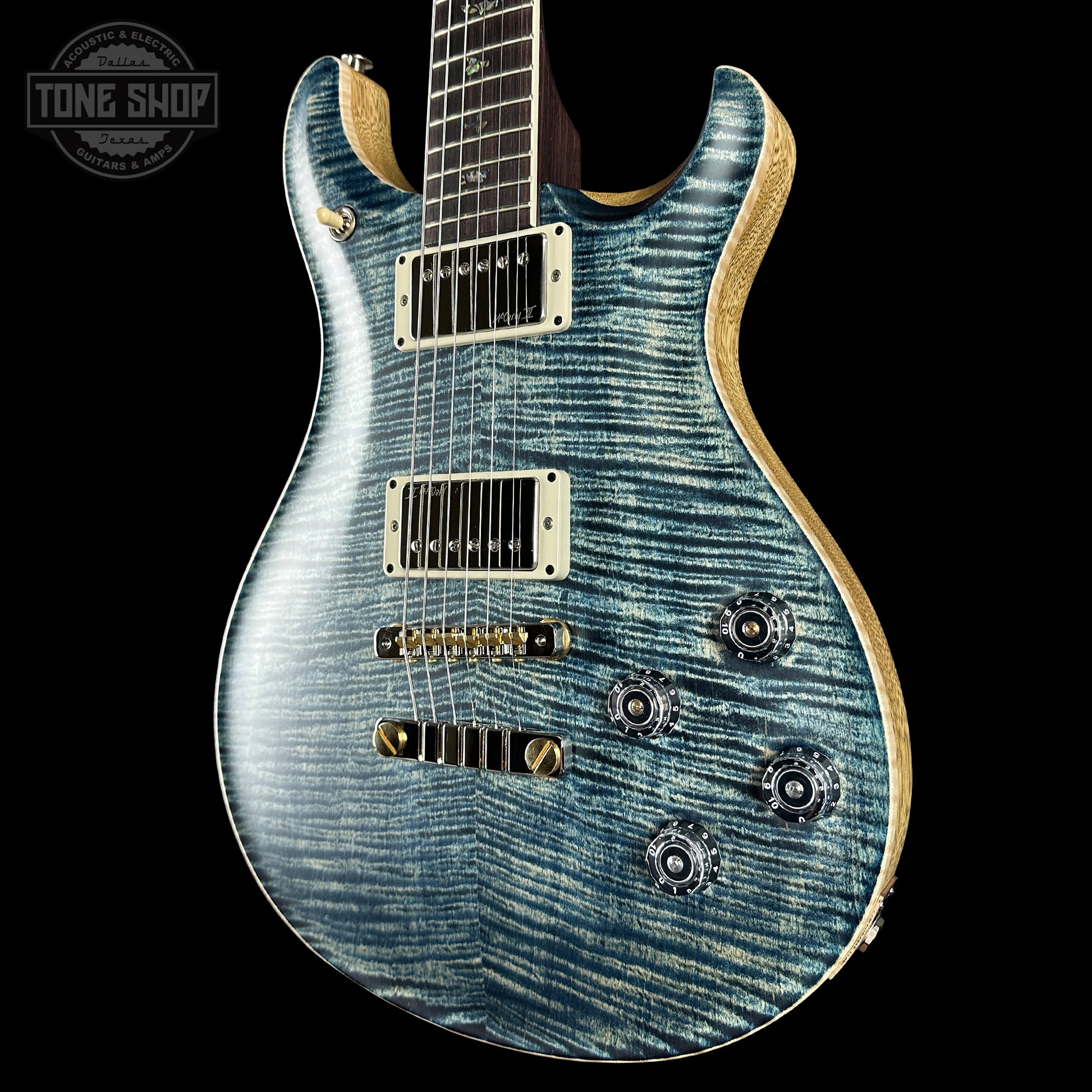 Blue electric guitar with a 'Tone Shop' logo in the corner