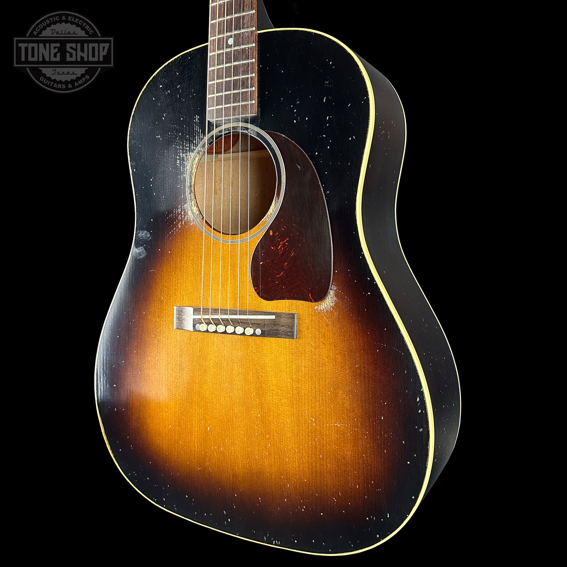 Acoustic guitar with a sunburst finish on a black background, featuring the Tone Shop logo.