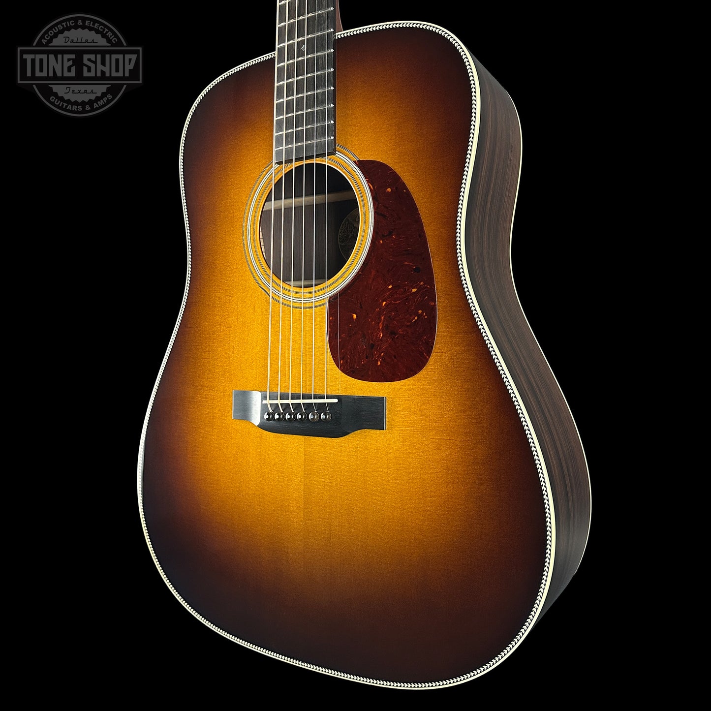 Acoustic guitar with a sunburst finish on a black background, featuring the Tone Shop logo.