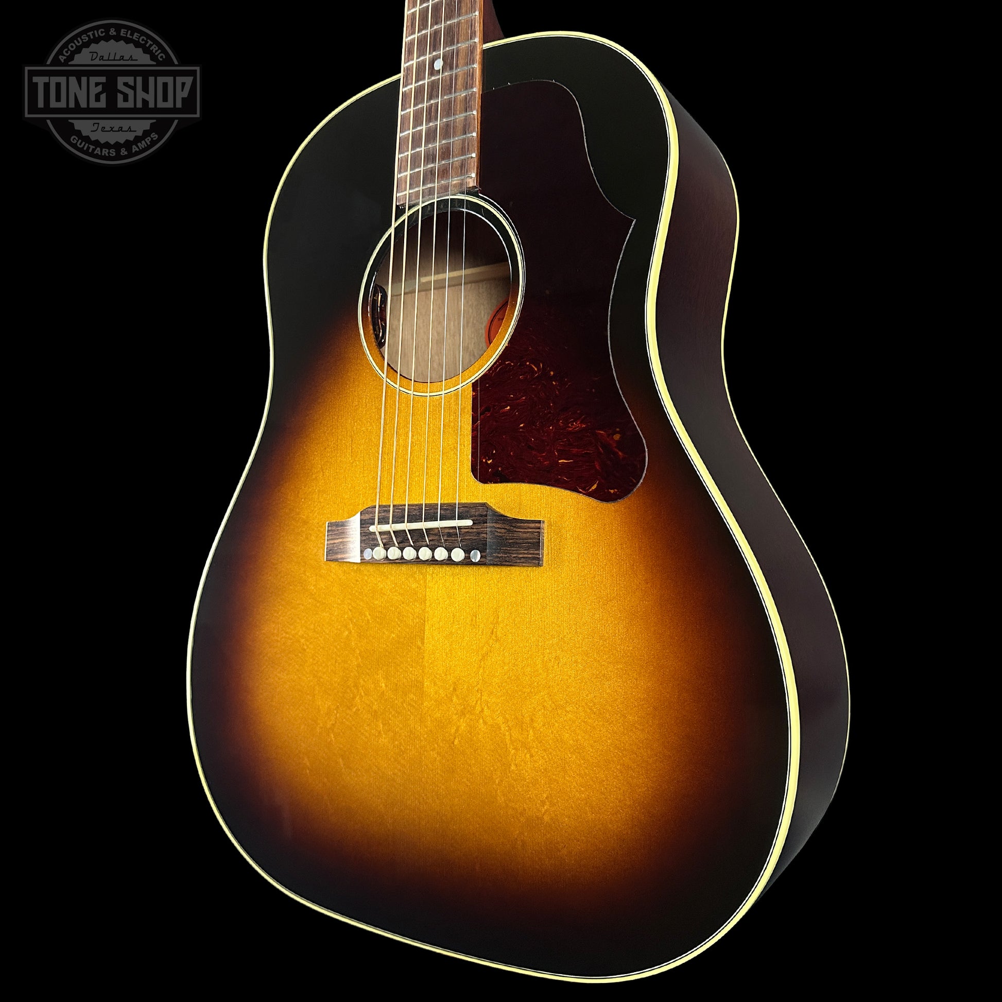 Acoustic guitar with a sunburst finish on a black background, featuring the Tone Shop logo.