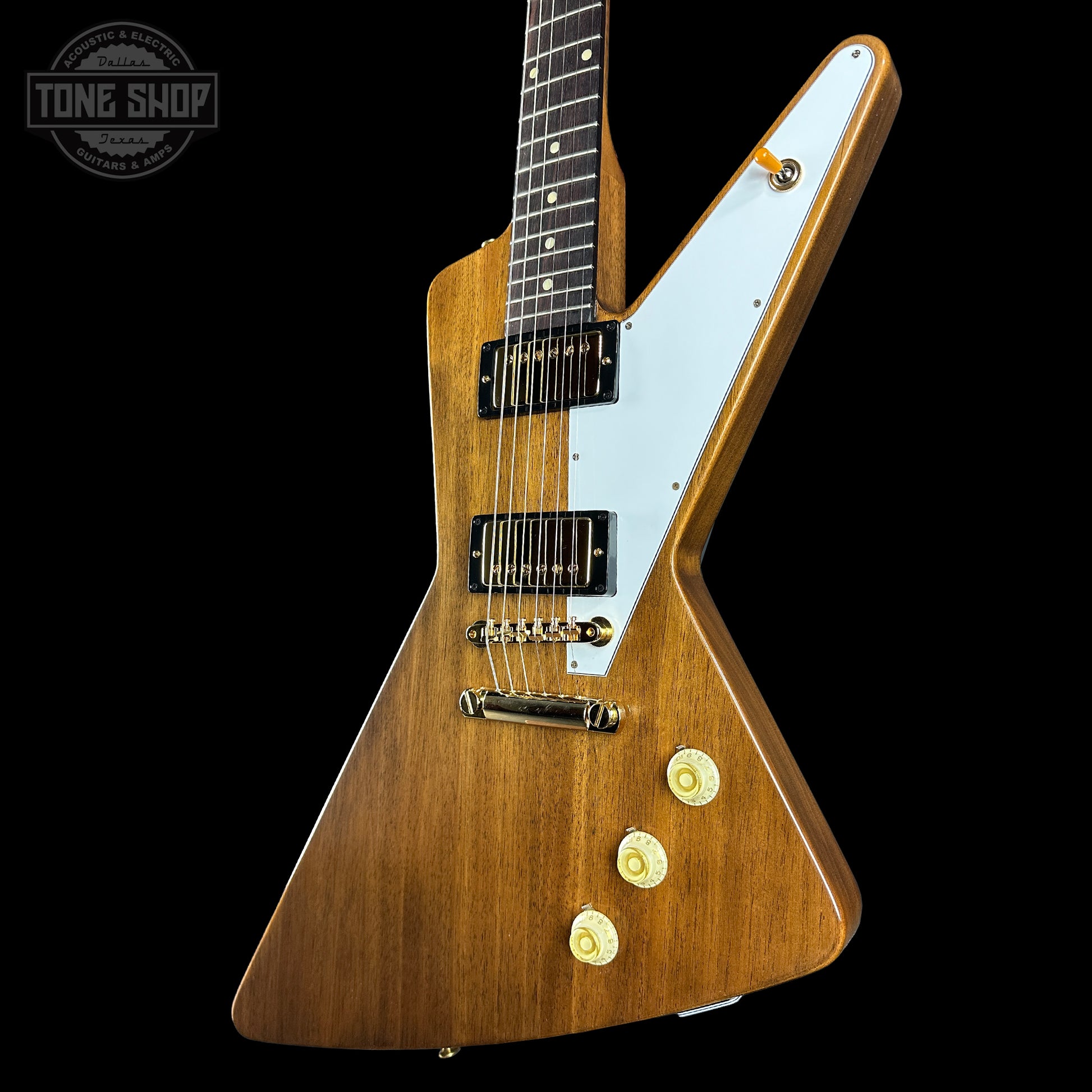 Wooden electric guitar with a white pickguard on a black background, featuring the Tone Shop logo.