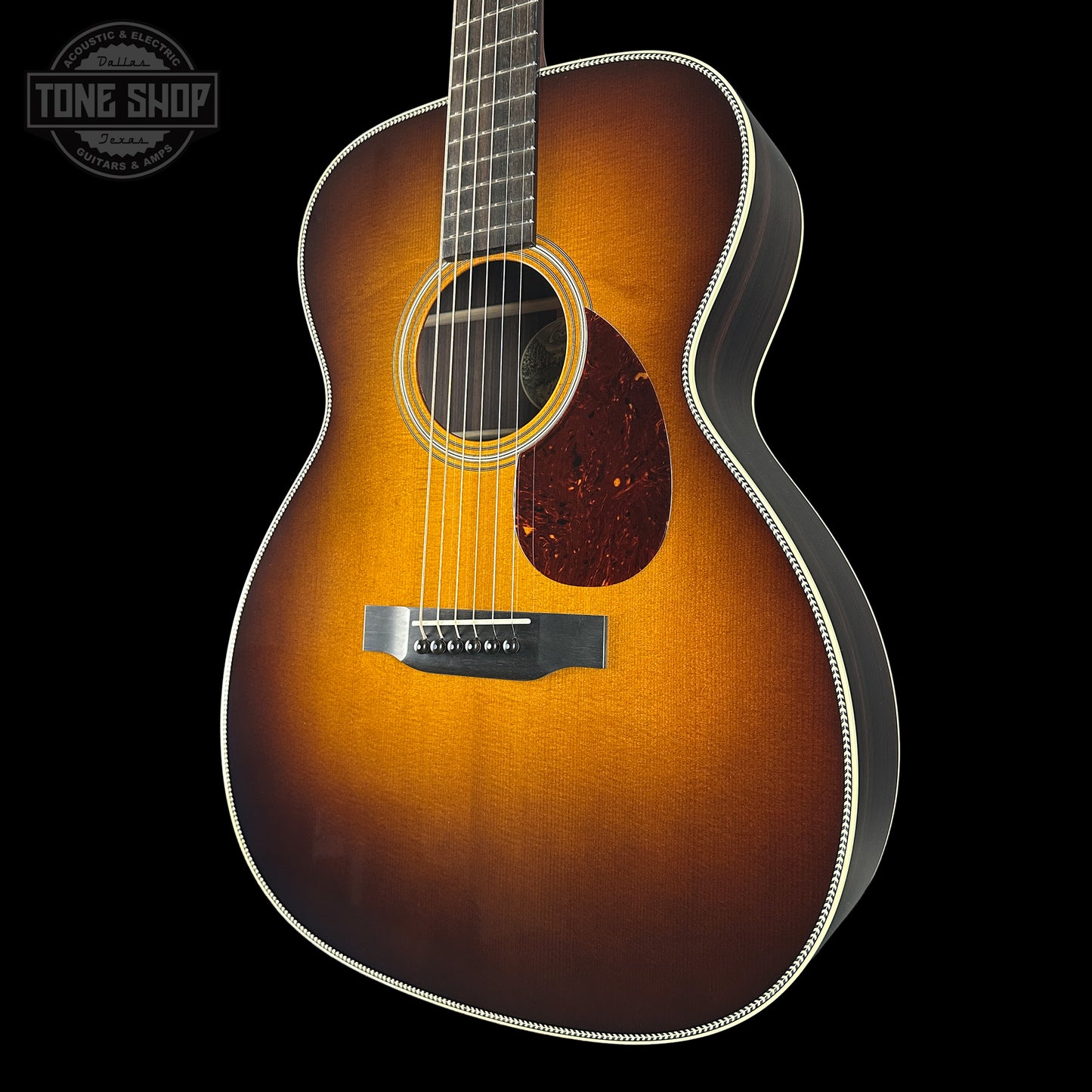 Acoustic guitar with a sunburst finish on a black background, featuring the Tone Shop logo.