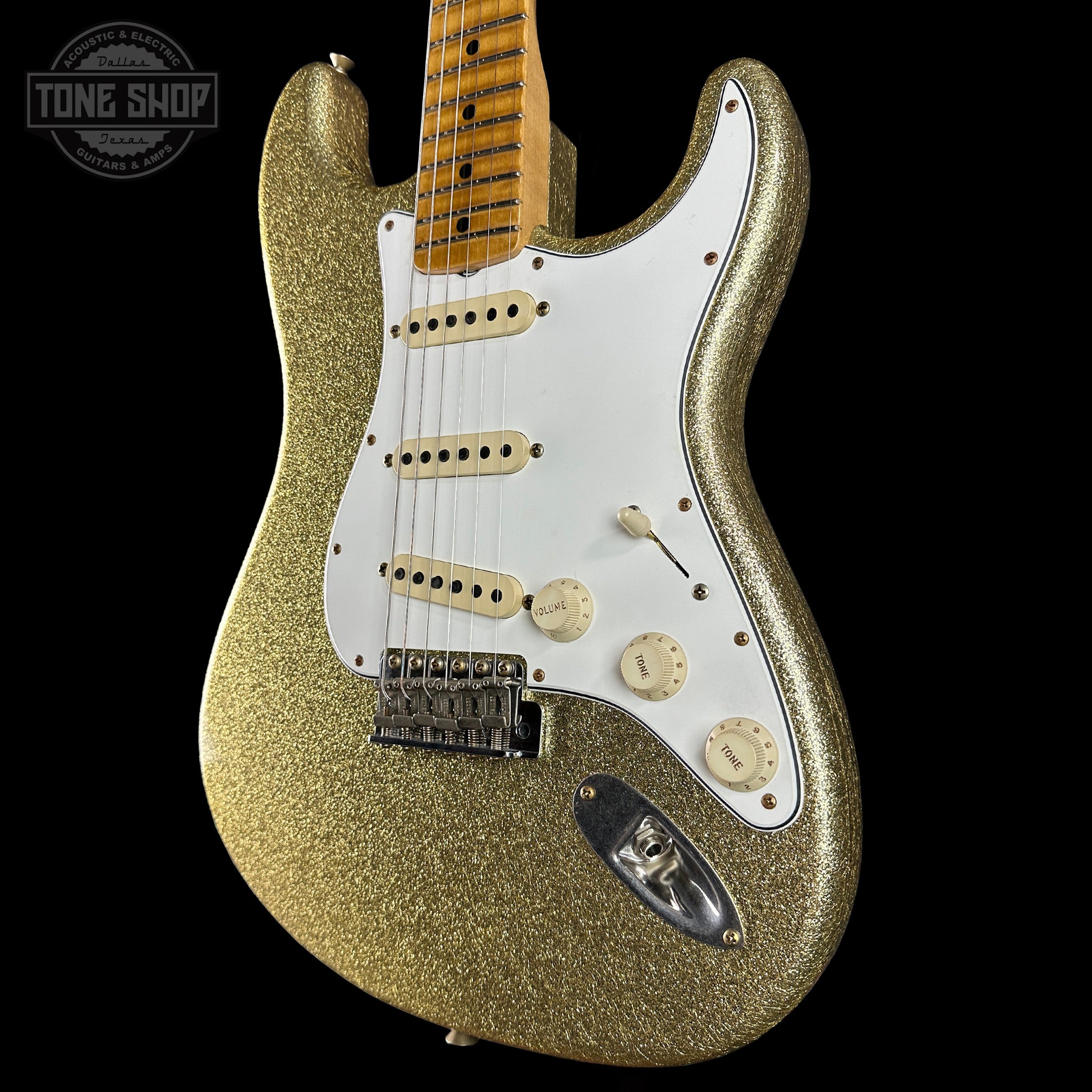 Gold glitter electric guitar with a white pickguard on a black background, featuring 'Tone Shop' logo.