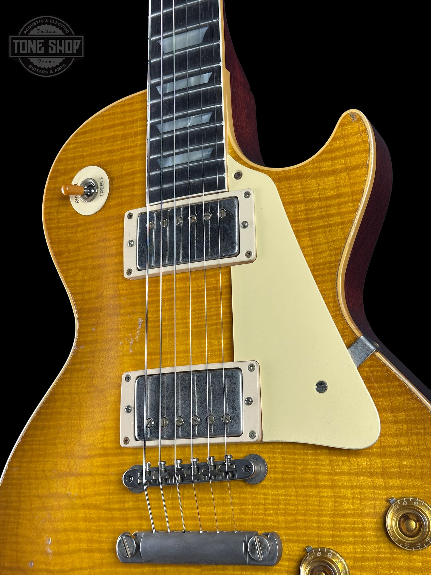 Close-up of a Les Paul electric guitar with a sunburst finish on a black background.