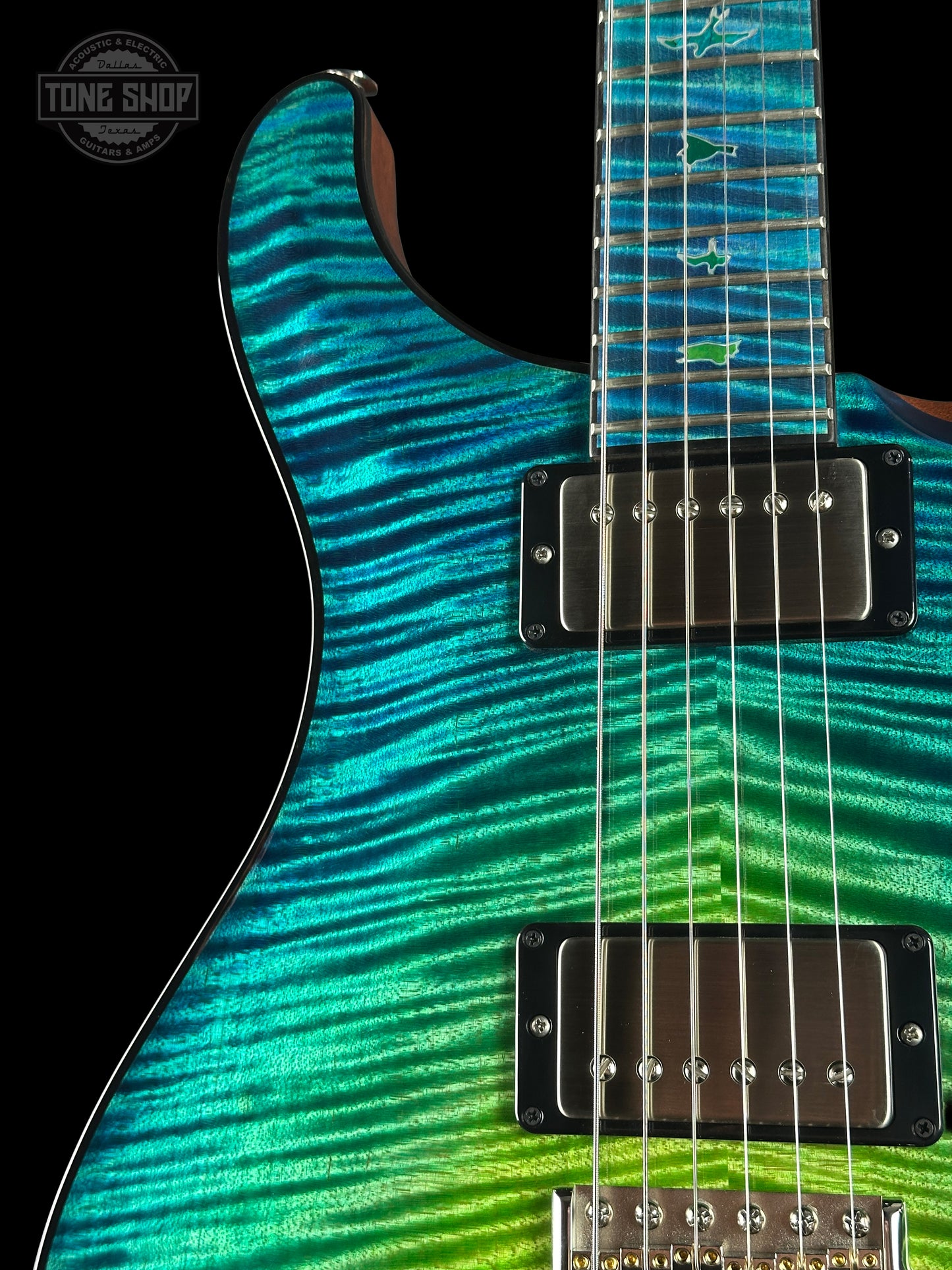 Close-up of a electric guitar with a vibrant blue and green striped pattern on a black background.