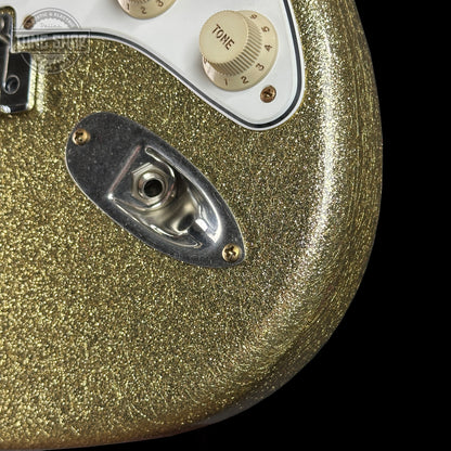 Close-up of a gold glittery guitar with control knobs on a black background