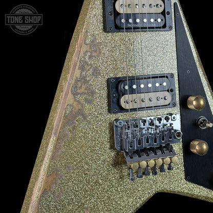 Close-up of a guitar with a glittery finish, pickups, and control knobs on a black background.