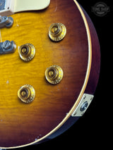 Close-up of a guitar with gold tuning pegs on a black background