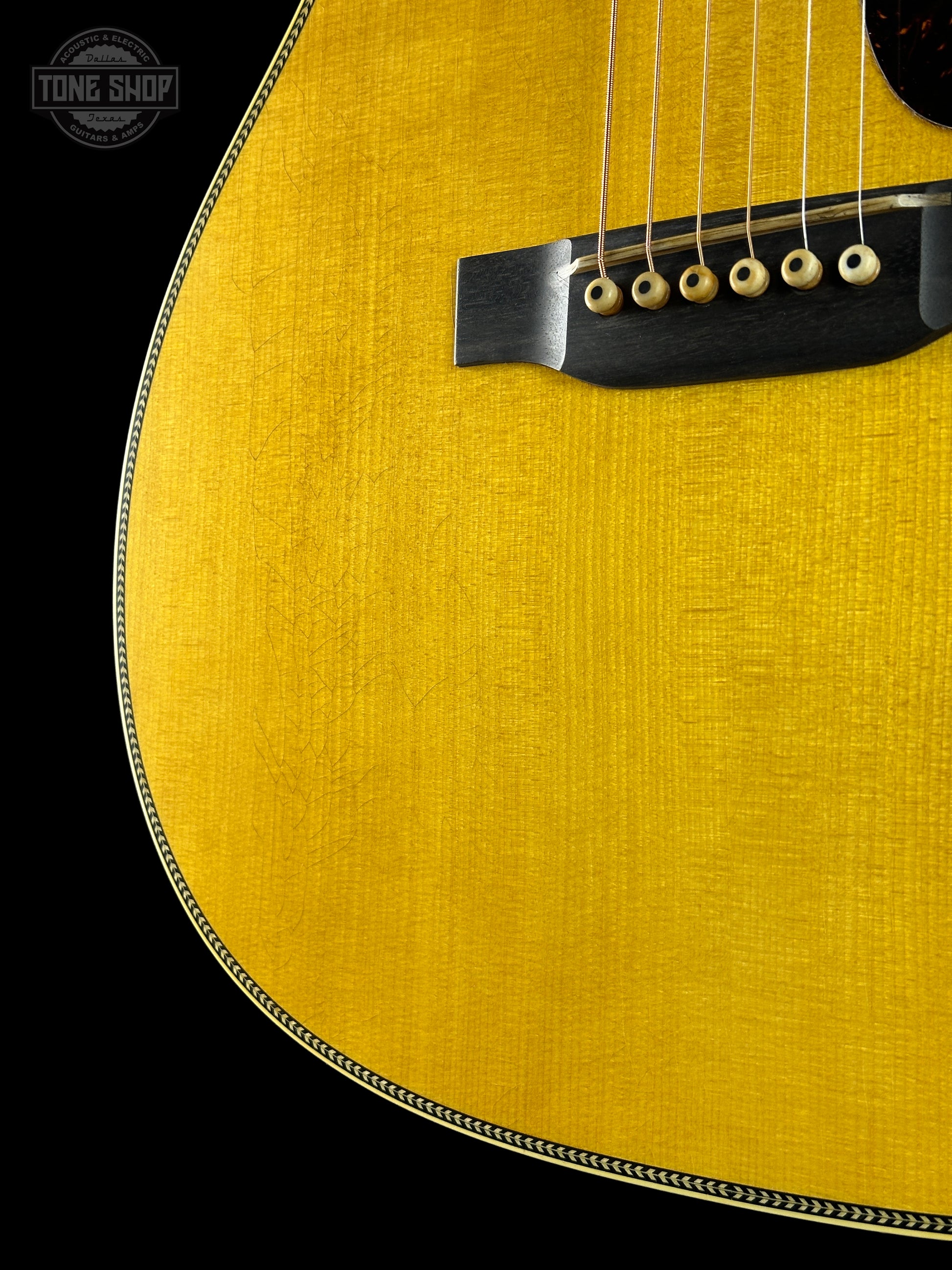 Close-up of a yellow acoustic guitar on a black background