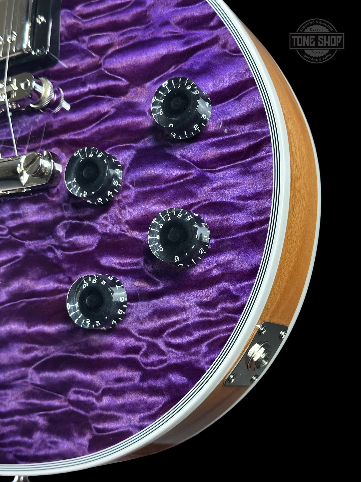 Close-up of a guitar headstock with purple pickguard and visible brand logo.