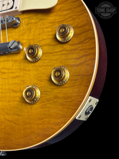 Close-up of a guitar with visible hardware and a 'Tone Shop' logo.