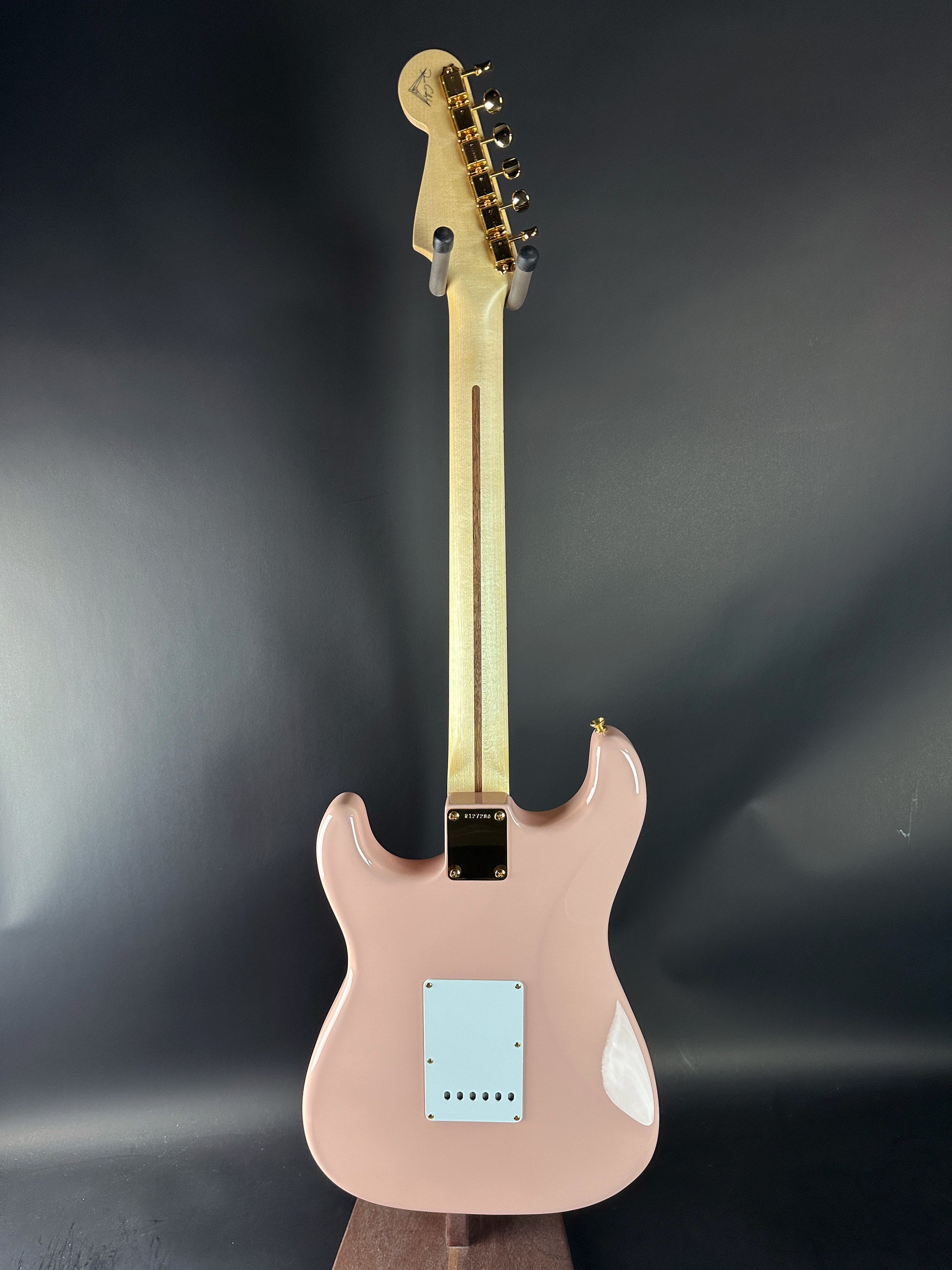 Pink electric guitar with a black pickguard on a dark gray background