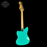 Turquoise electric guitar with wooden neck on a black background, featuring 'Tone Shop' logo.