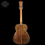 Back view of a wooden acoustic guitar with 'Tone Shop' logo in the corner.