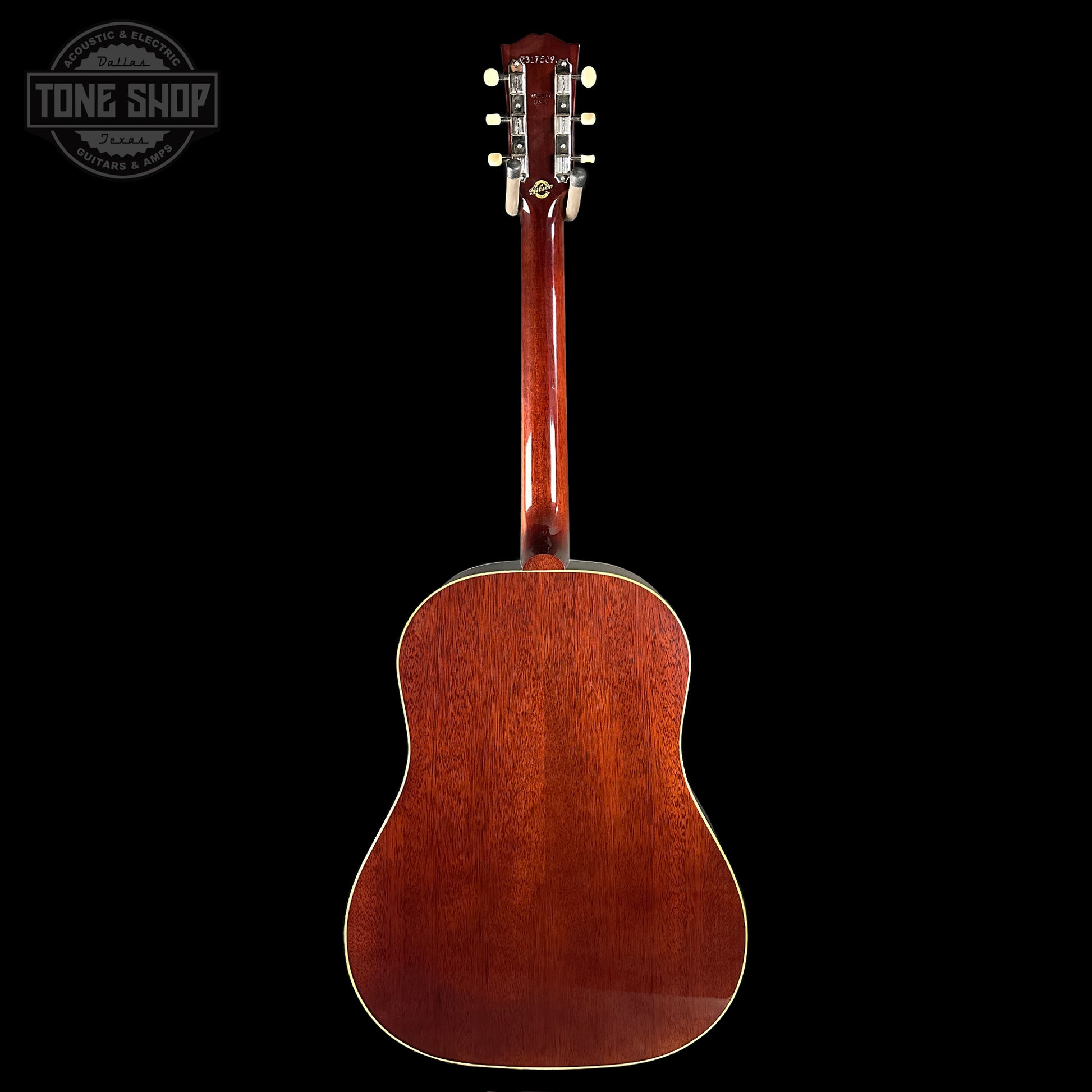 Back view of a wooden acoustic guitar with a dark background