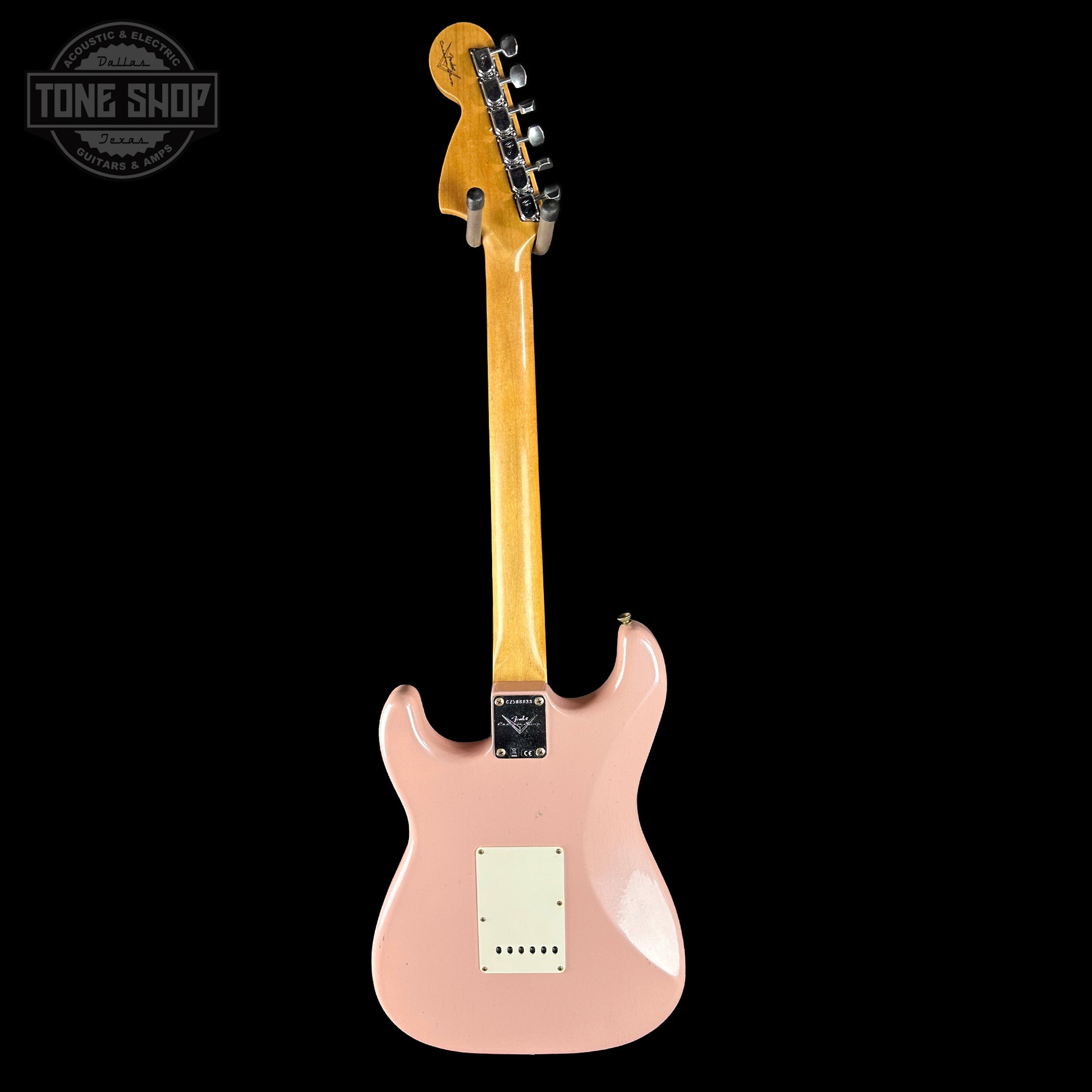 Pink electric guitar with a visible brand logo on a black background
